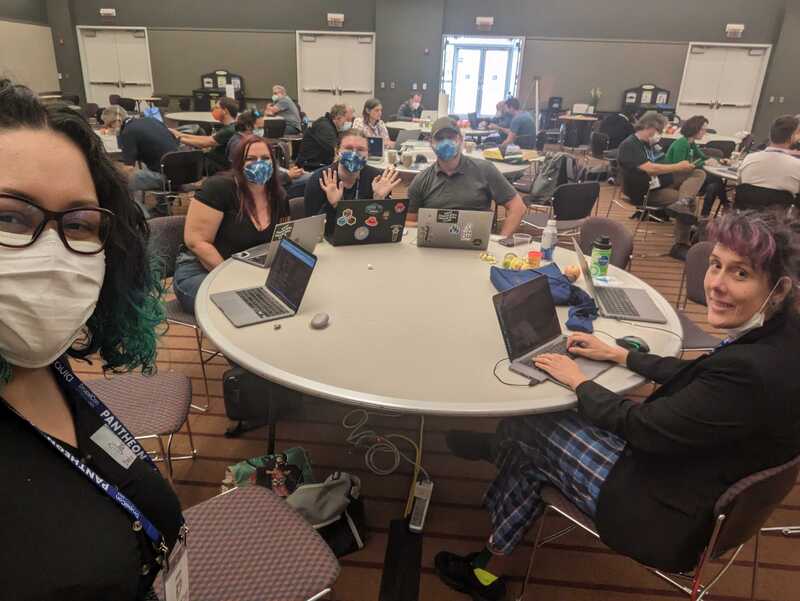 Une photo montrant les participants assis autour d’une table utilisant leurs ordinateurs durant la journée de contribution à la DrupalCon de Pittsburgh.